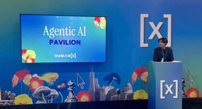 HumanX 2026 — Agentic AI Pavilion stage with the screen title card, speaker podium, and San Francisco skyline mural